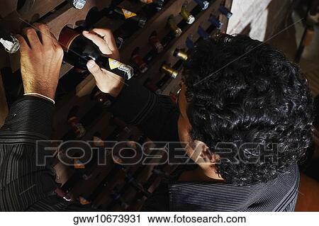 High angle view of a young man taking a bottle from a wine rack View Large Photo Image Stock Image - High angle view of a young man taking a bottle from a wine rack. Fotosearch