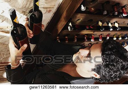 High angle view of a young man taking a bottle from a wine rack View Large Photo Image Stock Image - High angle view of a young man taking a bottle from a wine rack. Fotosearch