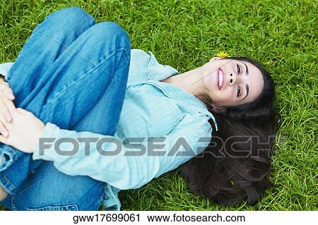 High angle view of a young woman lying on the grass and hugging her knees in the park View Large Photo Image Stock Image - High angle view of a young woman lying on the grass and hugging her knees in the park. Fotosearch