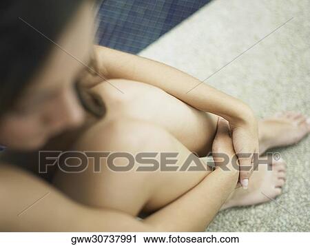 Stock Image - High angle view of a young woman sitting at the poolside. Fotosearch