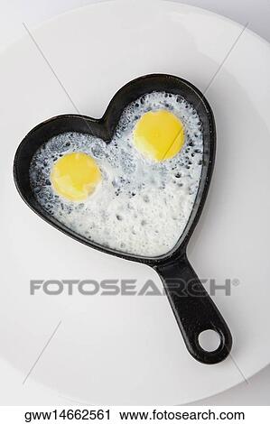 High angle view of fried eggs in a heart shaped frying pan View Large Photo Image Stock Image - High angle view of fried eggs in a heart shaped frying pan. Fotosearch