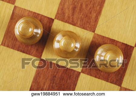 Stock Image - High angle view of three chess pieces on a chessboard. Fotosearch