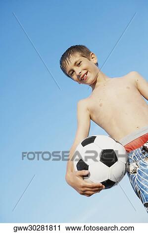 Low angle view of a boy holding a soccer ball View Large Photo Image Stock Image - Low angle view of a boy holding a soccer ball. Fotosearch
