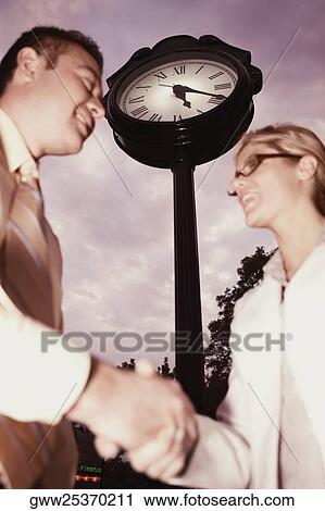 Stock Image - Low angle view of a businessman and a businesswoman shaking hands. Fotosearch