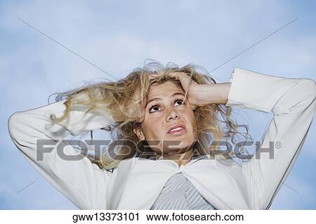 Stock Image - Low angle view of a businesswoman pulling her hair in frustration. Fotosearch