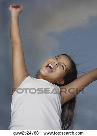 Low angle view of a girl standing with her arms raised View Large Photo Image Stock Image - Low angle view of a girl standing with her arms raised. Fotosearch
