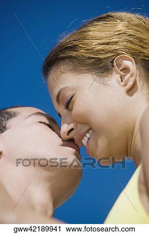 Stock Image - Low angle view of a mid adult man and a young woman kissing. Fotosearch
