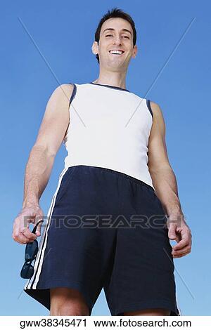 Stock Image - Low angle view of a mid adult man standing and smiling. Fotosearch