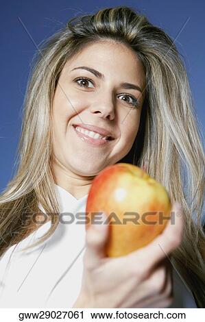 Stock Image - Low angle view of a mid adult woman holding an apple. Fotosearch