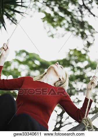 Low angle view of a mid adult woman sitting on a rope swing View Large Photo Image Stock Image - Low angle view of a mid adult woman sitting on a rope swing. Fotosearch