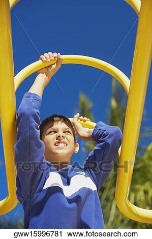 Low angle view of a teenage boy on a jungle gym View Large Photo Image Stock Image - Low angle view of a teenage boy on a jungle gym. Fotosearch