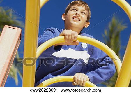 Low angle view of a teenage boy on a jungle gym View Large Photo Image Stock Image - Low angle view of a teenage boy on a jungle gym. Fotosearch