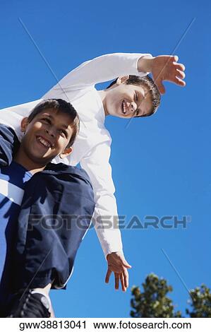 Low angle view of a teenage boy carrying his brother on his shoulders View Large Photo Image Stock Image - Low angle view of a teenage boy carrying his brother on his shoulders. Fotosearch