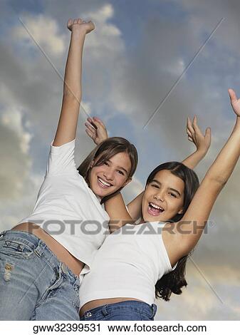 Low angle view of a teenage girl and her sister standing with her arms outstretched View Large Photo Image Stock Image - Low angle view of a teenage girl and her sister standing with her arms outstretched. Fotosearch