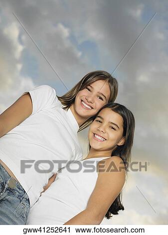 Low angle view of a teenage girl standing with her sister View Large Photo Image Stock Image - Low angle view of a teenage girl standing with her sister. Fotosearch