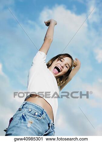 Low angle view of a teenage girl with her arms raised View Large Photo Image Stock Image - Low angle view of a teenage girl with her arms raised. Fotosearch