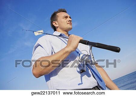 Low angle view of a young man holding a fishing rod View Large Photo Image Stock Image - Low angle view of a young man holding a fishing rod. Fotosearch