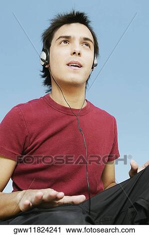 Low angle view of a young man listening to music View Large Photo Image Stock Image - Low angle view of a young man listening to music. Fotosearch