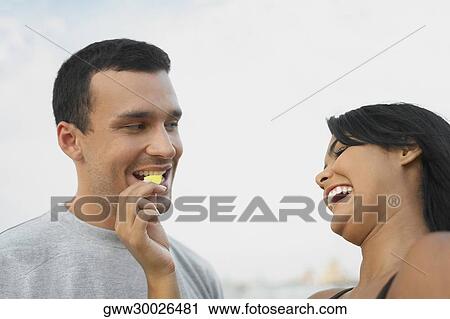 Low angle view of a young woman feeding a potato chip to a young man View Large Photo Image Stock Image - Low angle view of a young woman feeding a potato chip to a young man. Fotosearch