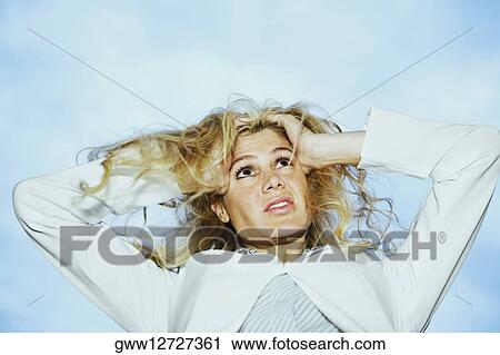Low angle view of a young woman holding her head View Large Photo Image Stock Image - Low angle view of a young woman holding her head. Fotosearch