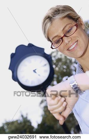 Low angle view of a young woman checking the time View Large Photo Image Stock Image - Low angle view of a young woman checking the time. Fotosearch