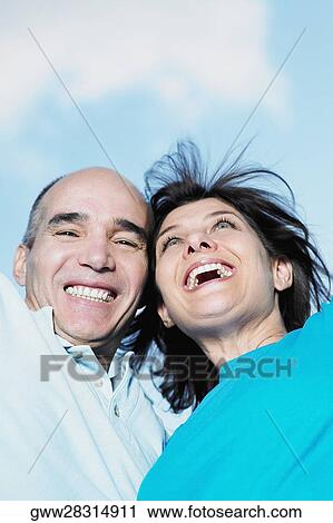 Low angle view of mature couple with their arms raised View Large Photo Image Stock Image - Low angle view of mature couple with their arms raised. Fotosearch