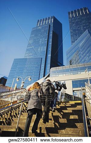Stock Image - Low angle view of men and women walking up stairs. Fotosearch