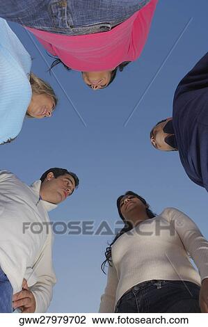 Low angle view of two mid adult men and a mid adult woman with two young women standing face to face View Large Photo Image Stock Image - Low angle view of two mid adult men and a mid adult woman with two young women standing face to face. Fotosearch