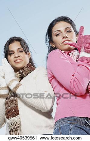 Low angle view of two young women standing View Large Photo Image Stock Image - Low angle view of two young women standing. Fotosearch