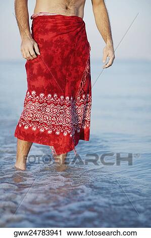 Stock Image - Low section view of a man standing in water. Fotosearch