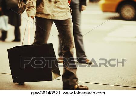 Low section view of a person carrying a shopping bag View Large Photo Image Stock Image - Low section view of a person carrying a shopping bag. Fotosearch