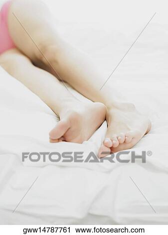 Low section view of a person lying on the bed View Large Photo Image Stock Image - Low section view of a person lying on the bed. Fotosearch