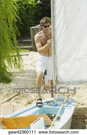 Mid adult man adjusting the sail of a sailboat View Large Photo Image Stock Image - Mid adult man adjusting the sail of a sailboat. Fotosearch