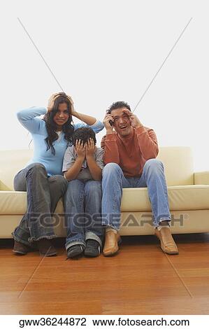 Mid adult man and a young woman with their son watching TV in fear View Large Photo Image Stock Image - Mid adult man and a young woman with their son watching TV in fear. Fotosearch