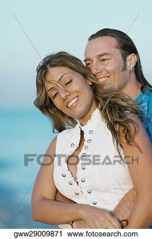 Mid adult man embracing a young woman from behind View Large Photo Image Stock Image - Mid adult man embracing a young woman from behind. Fotosearch