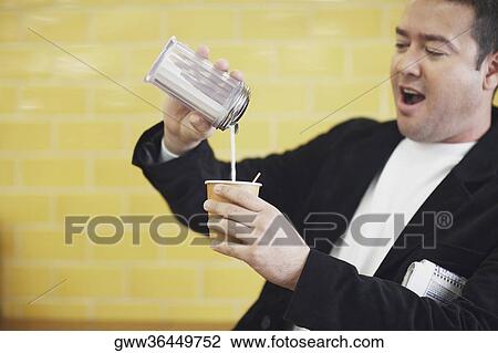 Mid adult man pouring milk into a disposable cup View Large Photo Image Stock Image - Mid adult man pouring milk into a disposable cup. Fotosearch