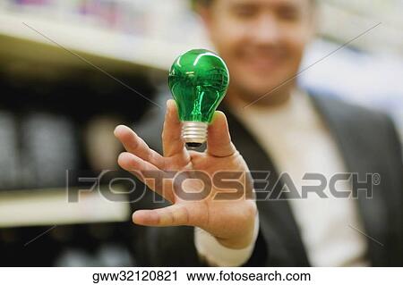 Mid adult man showing a light bulb View Large Photo Image Stock Image - Mid adult man showing a light bulb. Fotosearch