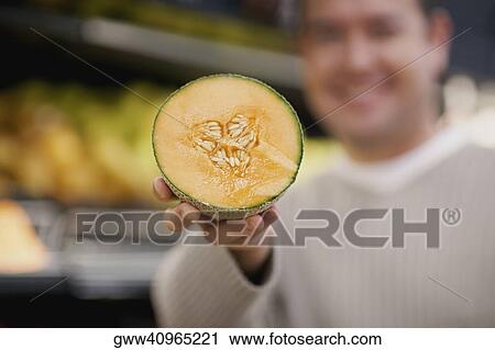 Mid adult man showing the cross section of a cantaloupe View Large Photo Image Stock Image - Mid adult man showing the cross section of a cantaloupe. Fotosearch