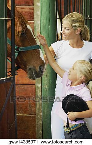 Mid adult woman and her daughter standing in a stable View Large Photo Image Stock Image - Mid adult woman and her daughter standing in a stable. Fotosearch