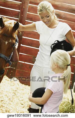 Mid adult woman and her daughter standing in a stable View Large Photo Image Stock Image - Mid adult woman and her daughter standing in a stable. Fotosearch