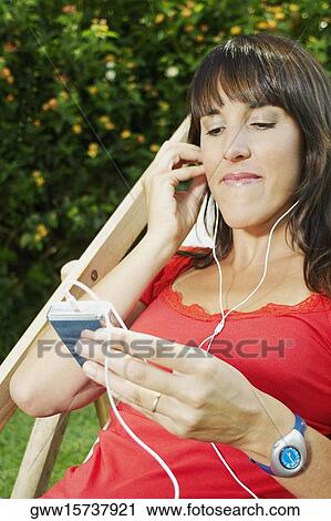 Stock Image - Mid adult woman listening to an mp3 player. Fotosearch
