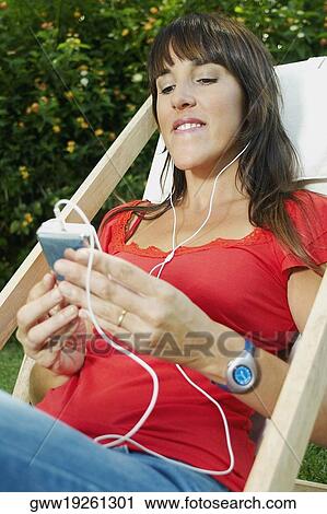 Mid adult woman listening to an mp3 player View Large Photo Image Stock Image - Mid adult woman listening to an mp3 player. Fotosearch