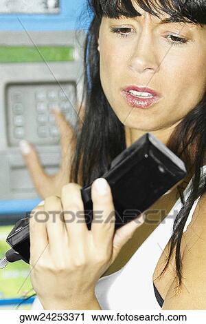 Mid adult woman looking at a telephone receiver View Large Photo Image Stock Image - Mid adult woman looking at a telephone receiver. Fotosearch