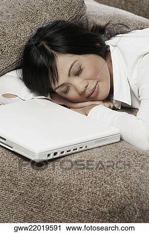 Mid adult woman sleeping on a couch with a laptop in front of her View Large Photo Image Stock Image - Mid adult woman sleeping on a couch with a laptop in front of her. Fotosearch