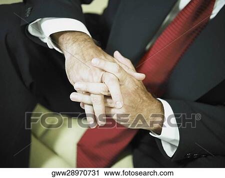 Stock Image - Mid section view of a businessman with his hands clasped. Fotosearch