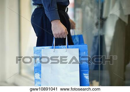 Mid section view of a man carrying shopping bags View Large Photo Image Stock Image - Mid section view of a man carrying shopping bags. Fotosearch