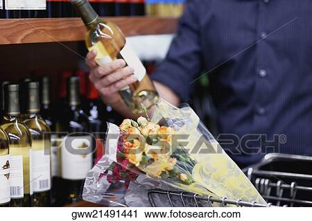 Mid section view of a man choosing a bottle of wine in a supermarket View Large Photo Image Stock Image - Mid section view of a man choosing a bottle of wine in a supermarket. Fotosearch