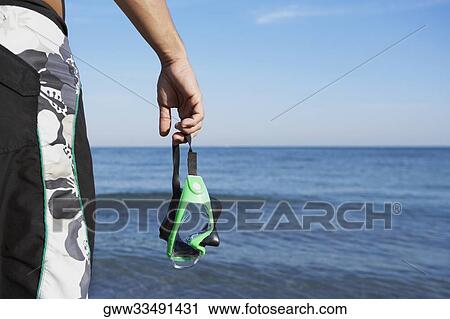 Mid section view of a man holding a swimming goggles View Large Photo Image Stock Image - Mid section view of a man holding a swimming goggles. Fotosearch