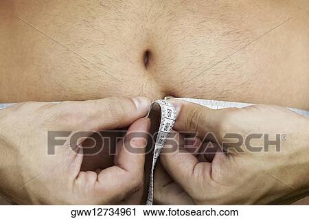 Mid section view of a man measuring his abdomen with a tape measure View Large Photo Image Stock Image - Mid section view of a man measuring his abdomen with a tape measure. Fotosearch