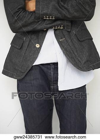 Stock Image - Mid section view of a man standing with his arm crossed. Fotosearch
